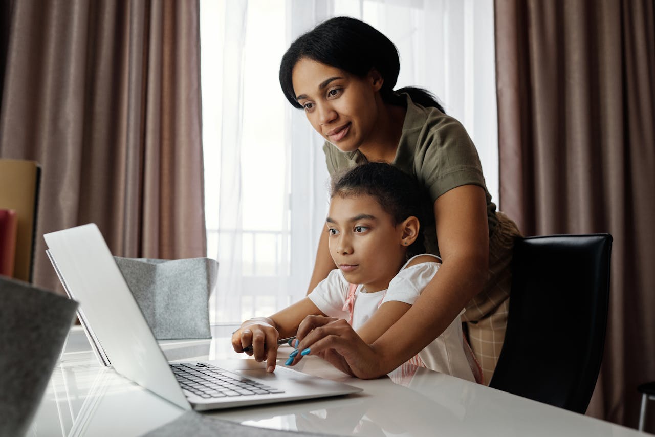 about-us A mother helps her daughter with an online lesson on a laptop, showcasing family bonding and education at home.